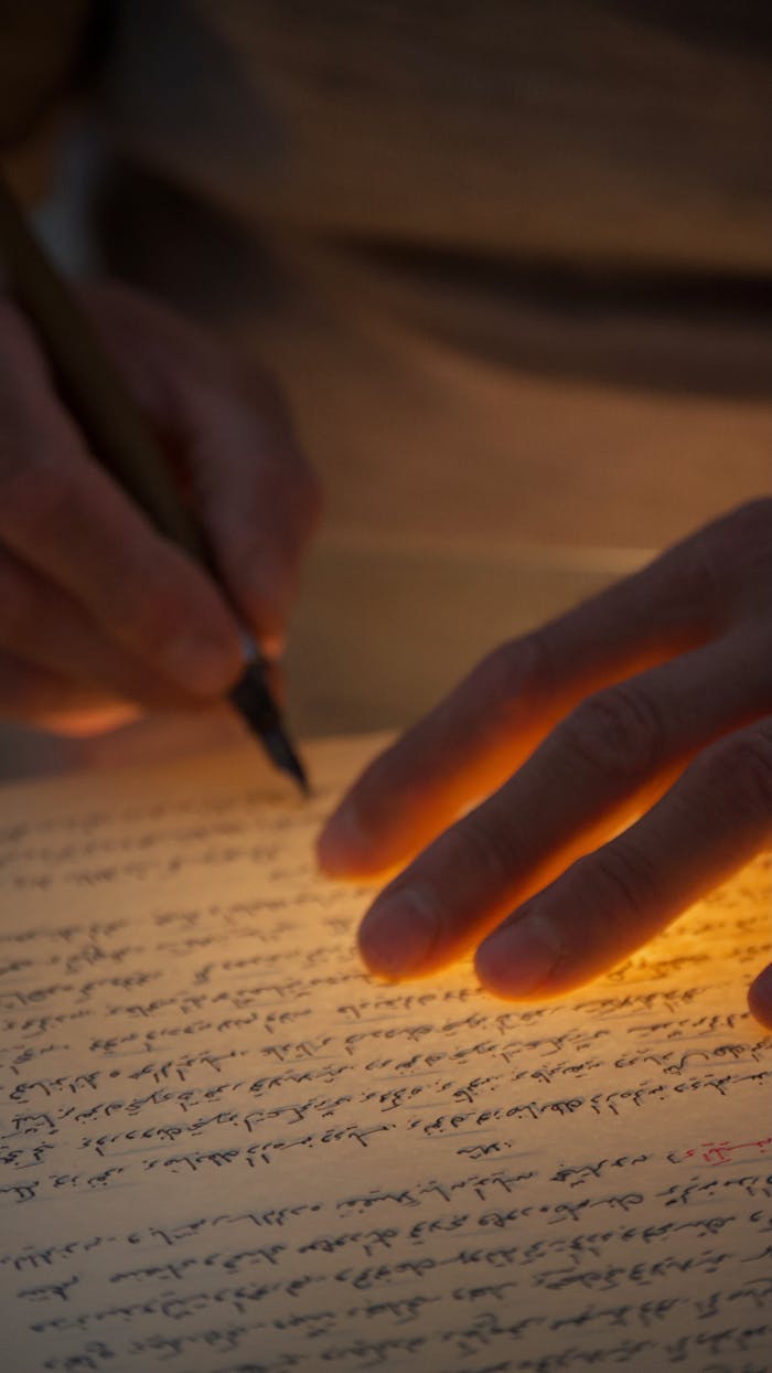 A hand writing on illuminated paper with warm, dramatic lighting effects.